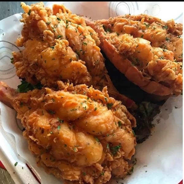 Golden fried chicken pieces topped with parsley, served on a patterned white plate.